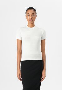 Hvid kortærmet top med et struktureret ribbet design, rund halsudskæring og tætsiddende silhuet, kombineret med en sort nederdel.