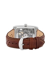 Brown perforated leather strap with cream stitching, silver stainless steel case, and visible mechanical movements through the transparent back.