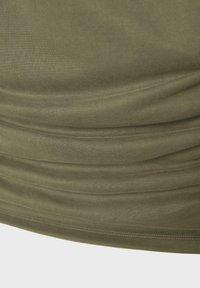 Gros plan d’un tissu vert olive avec des plis horizontaux froncés et une couture visible le long du bord inférieur.