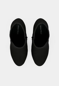 Zapatos negros de punta cerrada con un upper de tejido suave, que presentan un silueta bajo y una correa decorativa con hebilla a lo largo del costado.