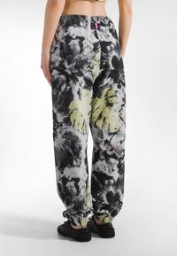 Mustat, harmaat ja keltaiset juoksuhousut kukkakuviolla. Kuminauhavyötärö ja -resorit lahkeissa. Kevyt kangas, rento istuvuus ja sivutaskut.