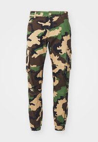 Heren camouflage cargo broek met elastische boorden, meerdere zakken, knoopsluiting en een patroon van groen, bruin, beige en zwart.