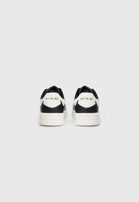 Black and white sneakers with a smooth leather finish, rounded shape, and a padded collar. Features "REPLAY" branding on the heel.