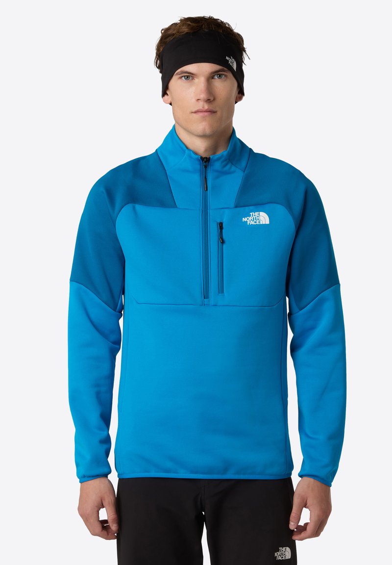 Pullover in fleece blu con colletto alto, mezza zip e tasca sul petto. Presenta pannelli a contrasto e un logo sul lato sinistro del petto.