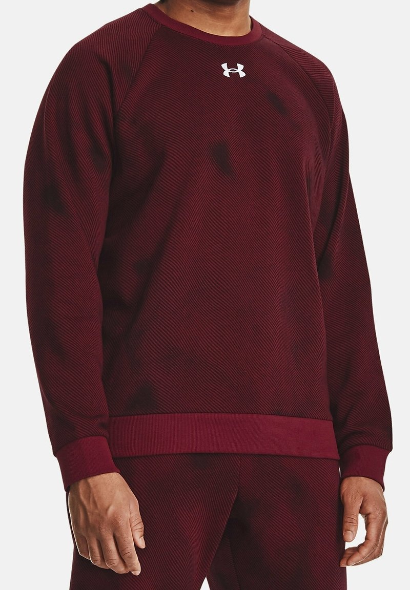 Burgundy atletisk sweatshirt med en texturerad ribbad design, rund halsringning och en kontrasterande vit logotyp på bröstet. Har åtsittande muddar och nederkant.