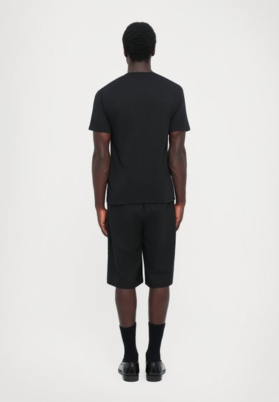 Schwarzes Baumwoll-T-Shirt und passende Shorts, beide mit einem schlichten Design. Das Shirt hat kurze Ärmel, während die Shorts knielang sind.
