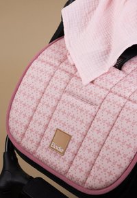 Pehmustettu vaaleanpunainen vauvanrattaiden istuin, jossa pieni kukkakuvio ja ruskea Elodie-etiketti, taiteltu vaaleanpunainen viltti päällä.