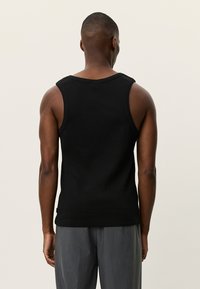 Μαύρο ριμπ τοπ με φαρδιές τιράντες, με στρογγυλή λαιμόκοψη και εφαρμοστή σχεδίαση. Το μοντέλο φαίνεται από πίσω.