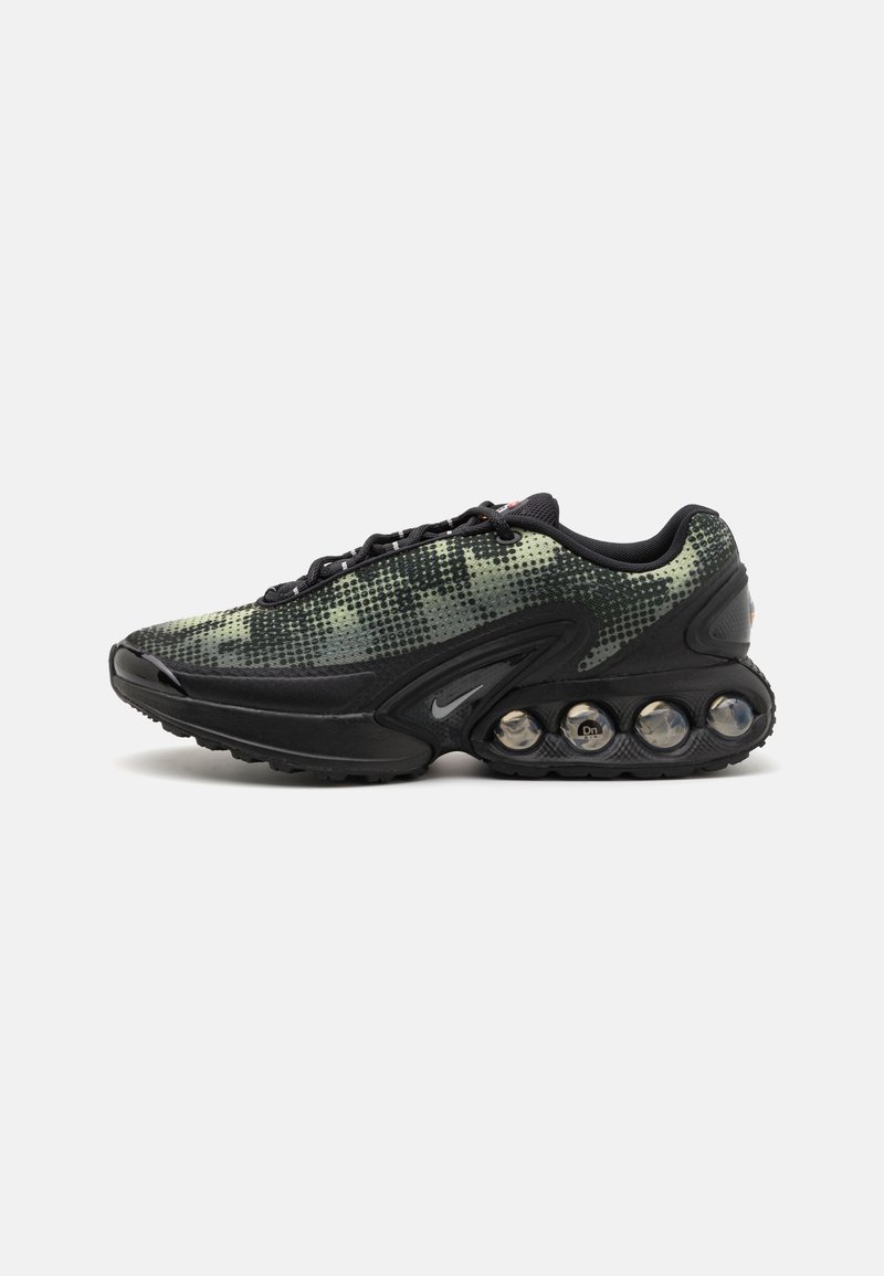 Chaussure de course Nike avec une tige en mesh de teintes noir et vert, présentant un motif texturé et des coussinets d'air visibles dans la semelle extérieure.