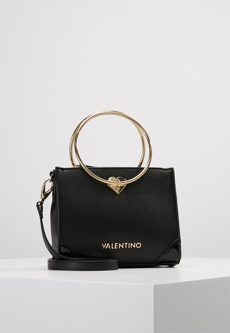 Svart läderhandväska med guldaccessoarer, utrustad med ett cirkulärt handtag och hjärtdetalj. Logotypen "VALENTINO" i guld framtill.