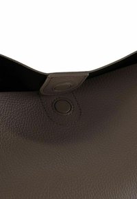 Bolso de cuero marrón con acabado texturizado, que cuenta con una solapa de cierre y un botón a presión circular. El interior es visible, destacando su diseño.