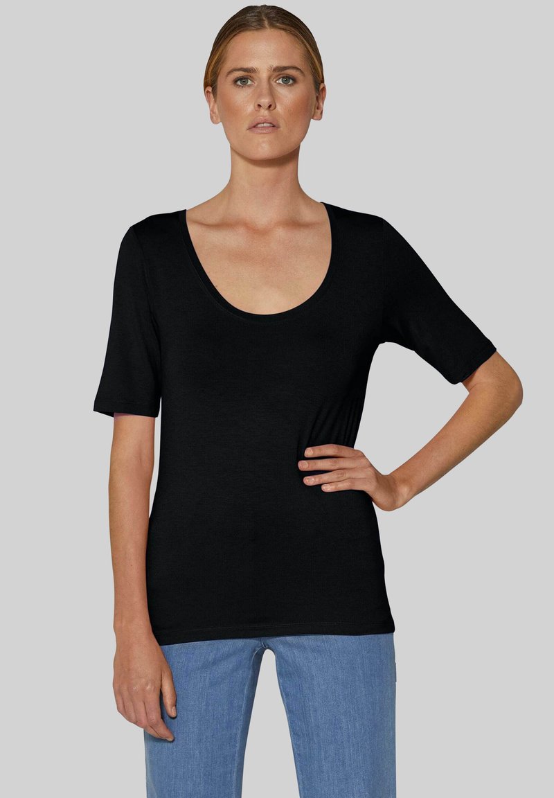 Schwarzes kurzärmliges T-Shirt mit weitem Rundhalsausschnitt, glatter Textur, taillierter Form und einer hellblauen Jeans.