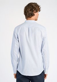 Camicia a righe blu chiaro e bianca con maniche lunghe, colletto button-down, piega sullo yoke posteriore e dettagli dell'orlo arrotondato. Materiale in cotone.
