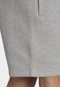 Pantaloni corti grigi in tessuto misto cotone, con taglio dritto, tasche laterali e una texture liscia. Design semplice senza motivi visibili.