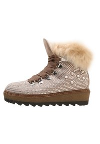 Bota de imitación de piel de fur marrón con un exterior texturizado en un beige claro adornado con embellishments plateados, que presenta un diseño de cordones y una suela gruesa y estriada.