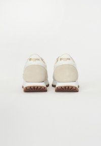 Scarpe sportive bianche con un tacco beige in suede, suola in gomma e logo dorato "Blauer USA" sul retro. Texture liscia con un design arrotondato.