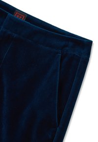 Marineblaue Samthose mit weicher Textur, ausgestattet mit einem flachen Bund und seitlichen Taschen. Deutlich sichtbares Markenlabel in der Nähe des Bundes.