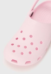 Pink rubber clog with perforated holes, textured accents, and a back strap for support. Smooth finish and rounded toe design.