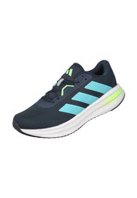 Zapatilla deportiva de malla azul con suela blanca, con detalles en turquesa y neón, y tres franjas diagonales en el lateral.