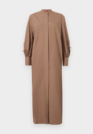 Robe longue marron avec col montant, manches longues bouffantes et broderies florales sur le haut des bras, présentée sur un fond uni.