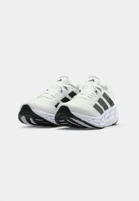 Witte sportieve schoenen met zwarte accenten, voorzien van een bovenwerk van mesh en een gestructureerde zool, ontworpen voor comfort en stabiliteit tijdens beweging.