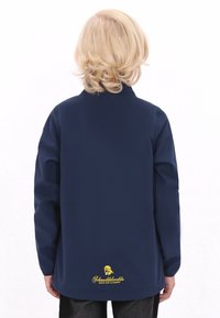 Marinblå jacka med krage, långa ärmar och en broderad logotyp i gult på baksidan, med en slät textur och enkel design.