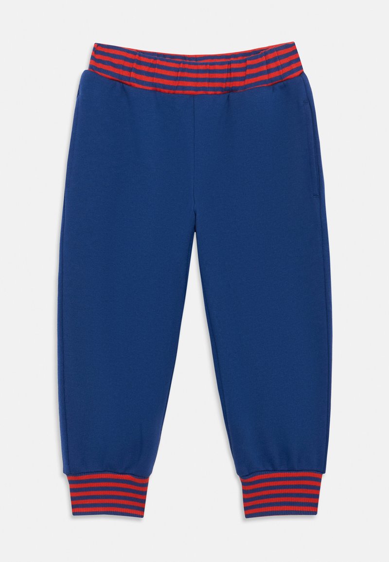 Pantalones de moletom azuis com faixa elástica vermelha e azul-marinho nas laterais e punhos, apresentando bolsos laterais.