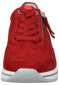 Zapatillas de ante rojo con cordones en la parte frontal, detalle de cremallera metálica en el lado y suela de goma blanca. Textura suave y forma redondeada.