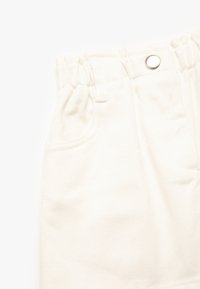 Weiße Baumwollhose mit strukturiertem Finish, mit einem elastischen Bund, einem silbernen Druckknopf und seitlichen Taschen.