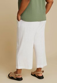 Vita linne culotter med en avslappnad passform, sidofickor och raka ben. Matchas med tan sandaler med korsande remmar.