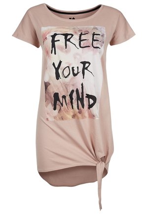 Chemise rose pâle à manches courtes avec texte "FREE YOUR MIND" et motif abstrait, présentant un détail noué en bas à droite.