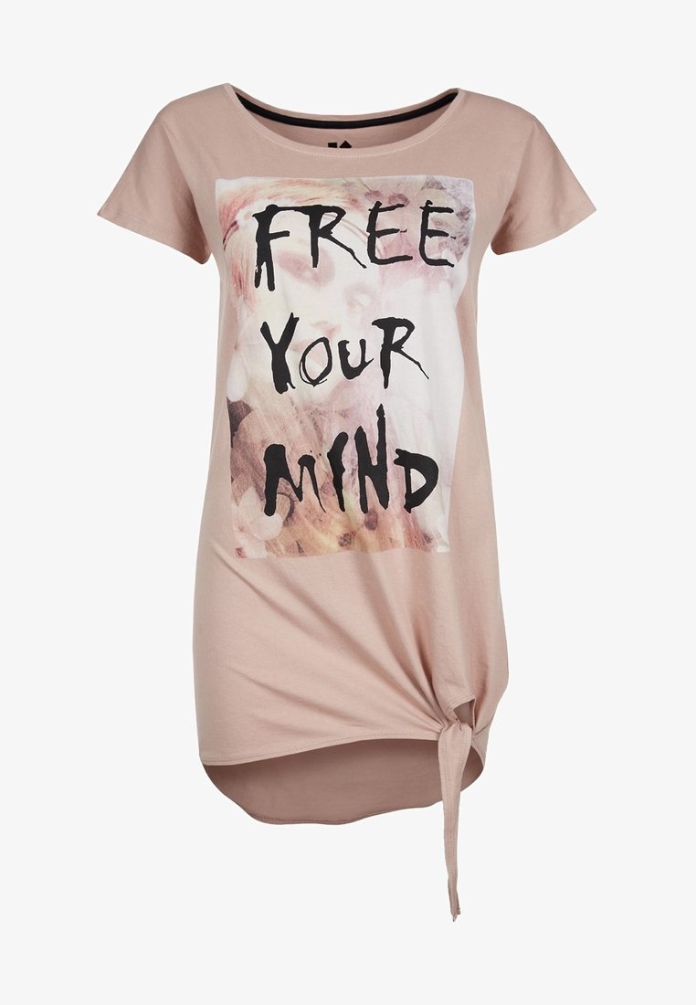 Chemise rose pâle à manches courtes avec texte "FREE YOUR MIND" et motif abstrait, présentant un détail noué en bas à droite.