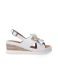 Witte wedge sandaal met een gestructureerd natuurlijk jute plateau, verstelbare enkelband en een decoratieve strikdetail op de voorband.