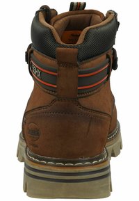 Botines de ante marrón con un collar negro texturizado, acentos en naranja y gris, y una suela de goma resistente. Presenta un tirador y una correa de seguridad.