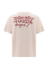 Béžové bavlněné tričko s červeným vyšitým textem na zadní straně, zobrazujícím jméno "Don Ed Hardy" a slovo "designs".