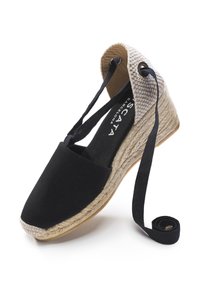 Sandalo con zeppa in tela nera, con tacco avvolto in juta, caratterizzato da dettagli intrecciati e un nastro nero per una calzata sicura.