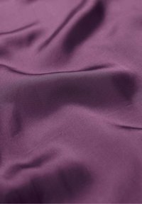 Tessuto viola con una texture liscia e opaca, che presenta pieghe e grinze delicate, esaltando la sua caduta morbida e la ricca profondità del colore.