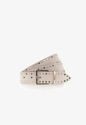 Cintura in suede beige chiaro con borchie rotonde in argento e oro, caratterizzata da una fibbia rettangolare argentata, arrotolata su uno sfondo bianco.