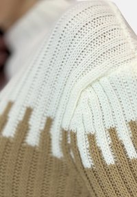 Stickad tröja med en design i kräm- och beige färgblock, med texturerad ribbning och ett mjukt, mysigt utseende.