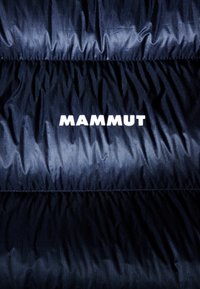 Granatowa kurtka puchowa z grubym pikowanym designem, gładkim, błyszczącym materiałem oraz wyraźnym białym logo "MAMMUT" wzdłuż dołu.