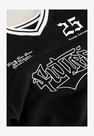 Maglia sportiva in rete nera con scollo a coste bianco, testo stilizzato audace in bianco "Forty5" e testo più piccolo "Twenty Four Seven 365 Collective Creative Future."