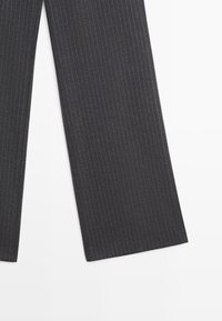 Pantaloni ampi grigio scuro con un delicato motivo a righe, caratterizzati da una trama liscia e orli puliti. Nessun hardware o accentuazione visibile.