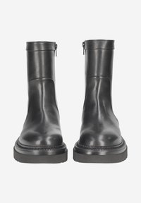 Black leather ankle boots with a smooth finish, featuring a zip closure at the back and a thick rubber sole with stitching detail.