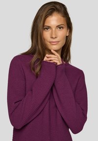 Lila strukturierter Pullover mit langen Ärmeln, entspannter Passform und runder Ausschnitt. Das Material scheint gestrickt zu sein mit gerippten Akzenten.