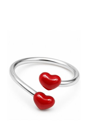 Bracelet jonc ouvert en argent avec deux extrémités brillantes en forme de cœur rouge sur fond blanc.