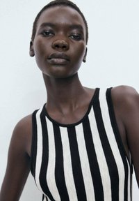 Black and white striped sleeveless top with a round neckline, made of soft fabric, featuring vertical stripes and a relaxed fit.