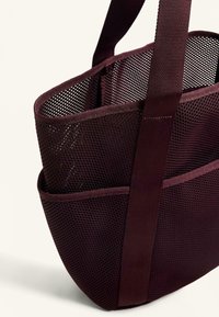 Bordowa torba siatkowa z szerokim otworem, jedną rączką i zewnętrzną kieszenią. Posiada strukturalny kształt i trwały syntetyczny materiał.
