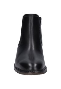 Černá kožená kotníková bota s hladkým povrchem, zaoblenou špičkou a bočním zipem. Má plochou podrážku s kontrastním světle hnědým okrajem.