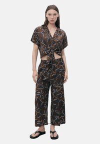 Brown floral print two-piece outfit featuring a knotted short-sleeve top and wide-leg pants. Made of lightweight fabric, with blue and white accents.