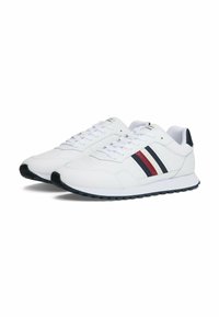 Witte sportieve schoenen met drie horizontale strepen in marineblauw, rood en crème. Gemaakt van glad leer, met een geprofileerde zwarte rubberen zool.